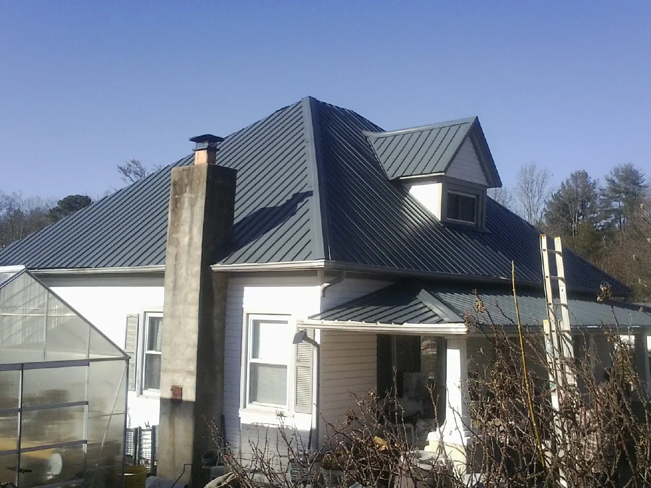 Dark blue standing seam metal roof on a white farmhouse with dormer — Slate & Tile Roof Repair by Roofing Brothers in March Air Reserve Base