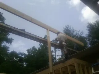 Carpenter setting a ridge beam over a new addition frame — Ice Dam Removal by Roofing Brothers in March Air Reserve Base