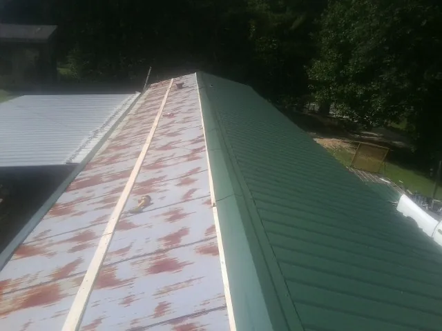 Old rusted panels beside newly installed green metal roofing — Wind Damage Roof Repair by Roofing Brothers in March Air Reserve Base