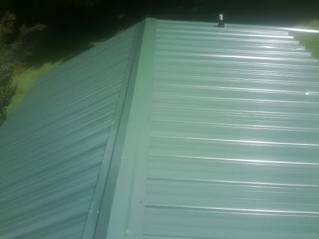 New green metal panels meeting at the ridge of a roof — Flat Roof Repair work by our crew in March Air Reserve Base