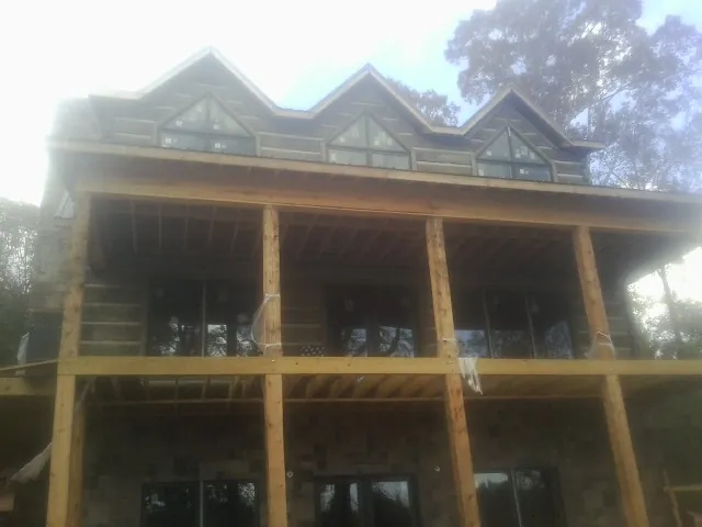 Dormers and porch framing on a large log home under construction — Roof Coating work by our crew in March Air Reserve Base