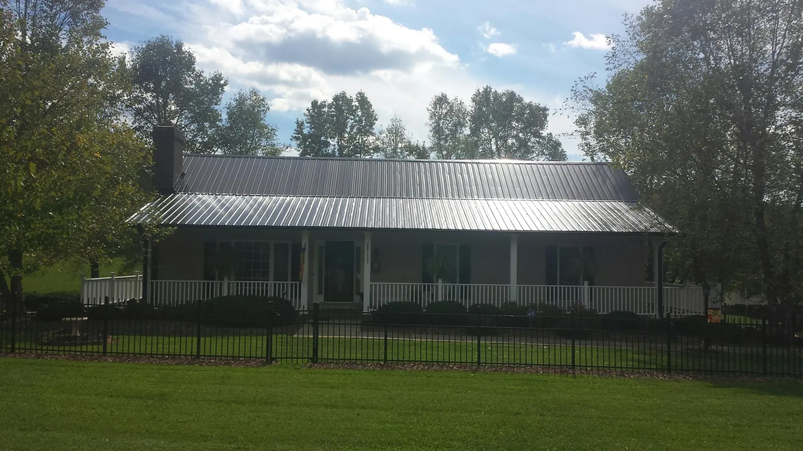 Gray metal roof on a brick ranch with a full width front porch — Gutter Guard Installation work by our crew in March Air Reserve Base