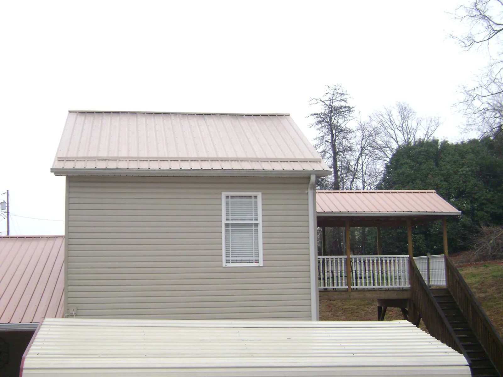Tan metal roofs on a two story addition and attached porch, from a Roof Replacement job in March Air Reserve Base