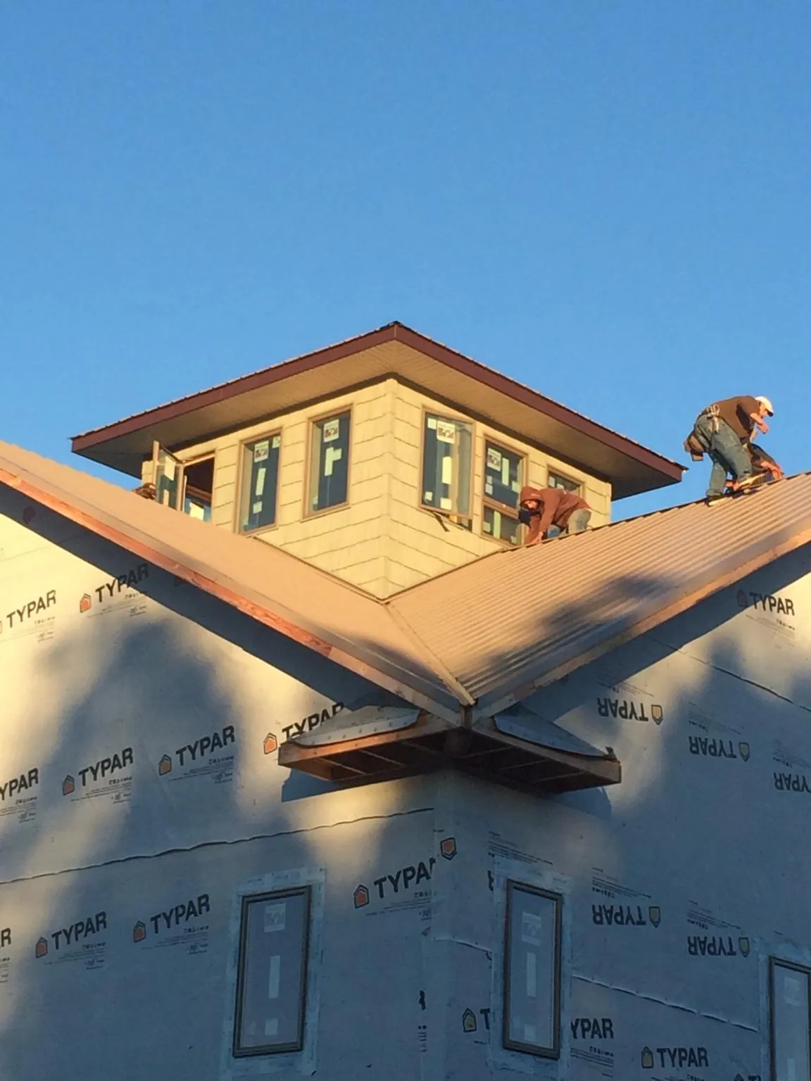 Roofers working around a rooftop cupola on a new metal roof at sunset — Roof Waterproofing in March Air Reserve Base by Roofing Brothers